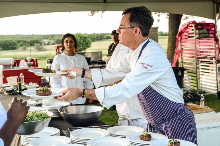 A chef with plates of meat prepared for Field to Fork.