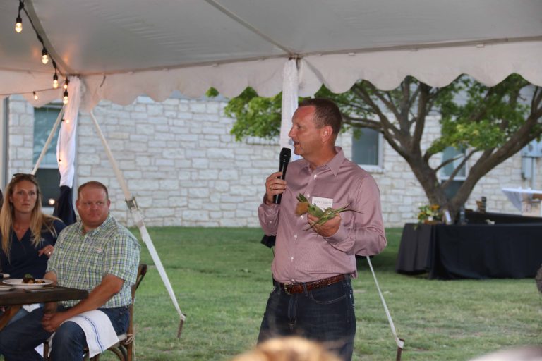 Rodney Schronk, a Texas farmer, speaks to Field to Fork guests shows the difference between corn varieties.