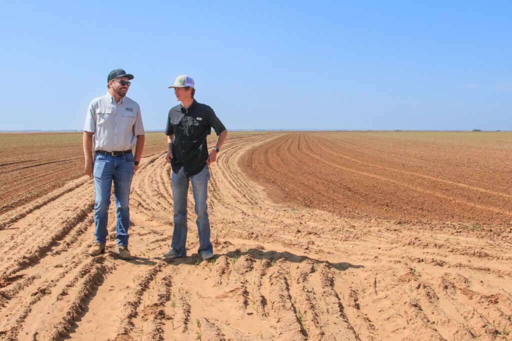 Two men walk through a field in Texas.