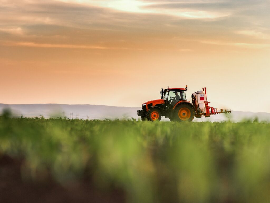 Tractor spraying pesticides on corn field with sprayer at spring