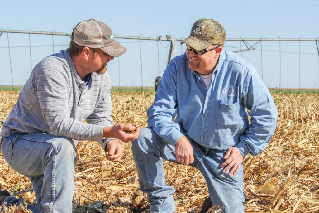 Farmers talk in a field.