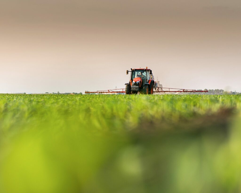 Tractor spraying pesticides on corn field with sprayer at spring